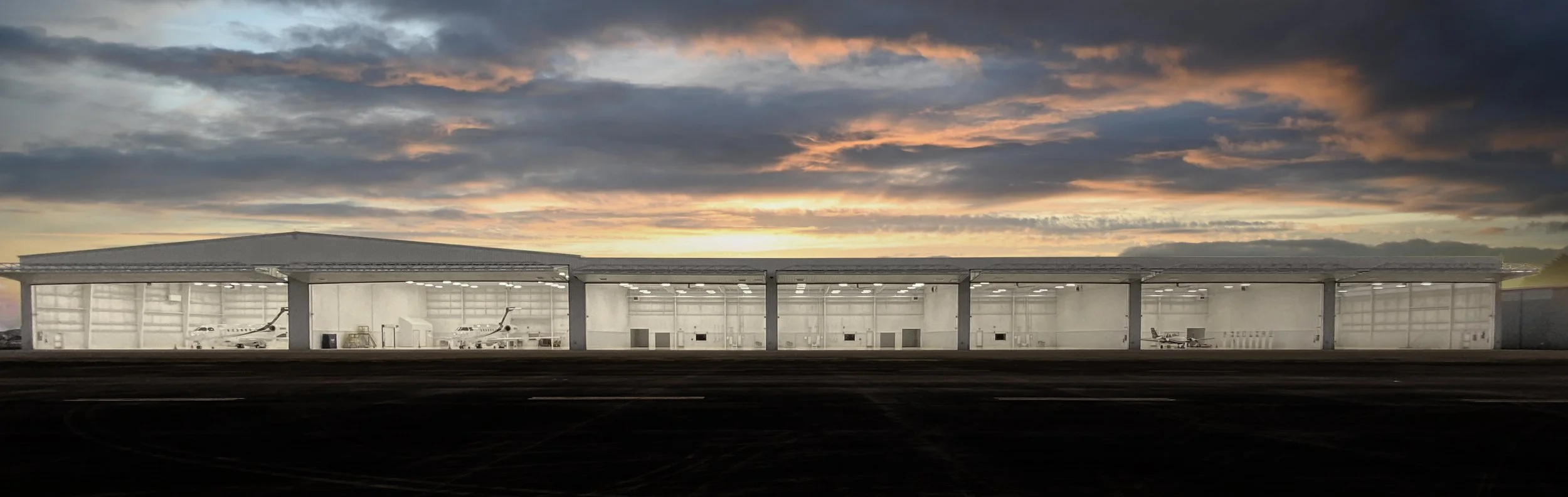 Houston 4 Panoramic view of a row of lit hangars under a colorful sunset sky