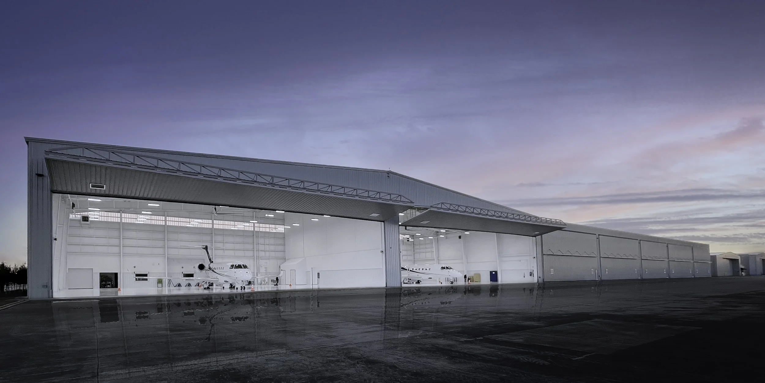 Houston 2 Sky Harbour hangar with open doors at sunset reflected on wet pavement