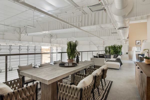 Mezzanine lounge with a dining table and leather chairs overlooking the hangar