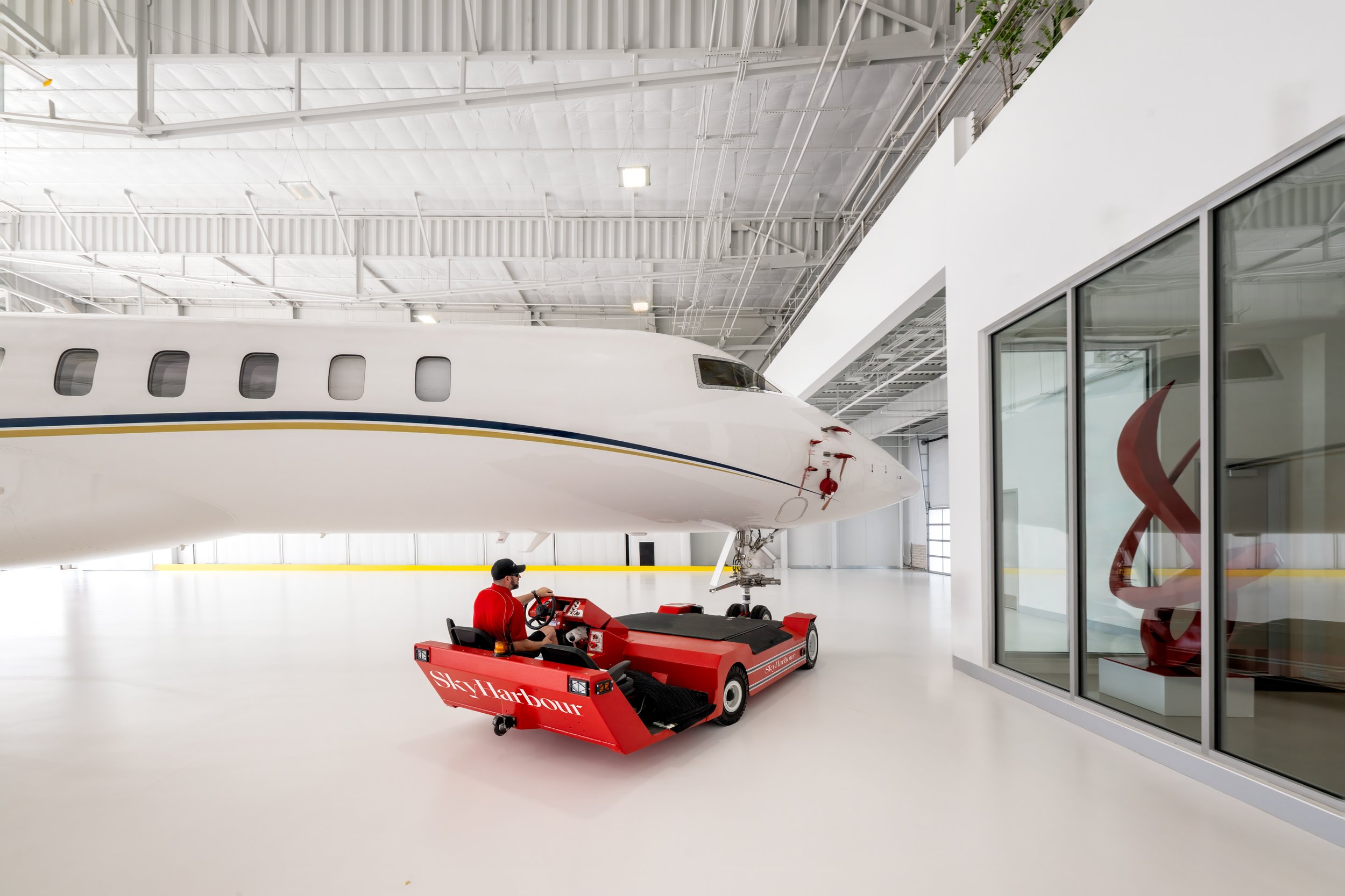 Private jet in a hangar with a red tug in front of it