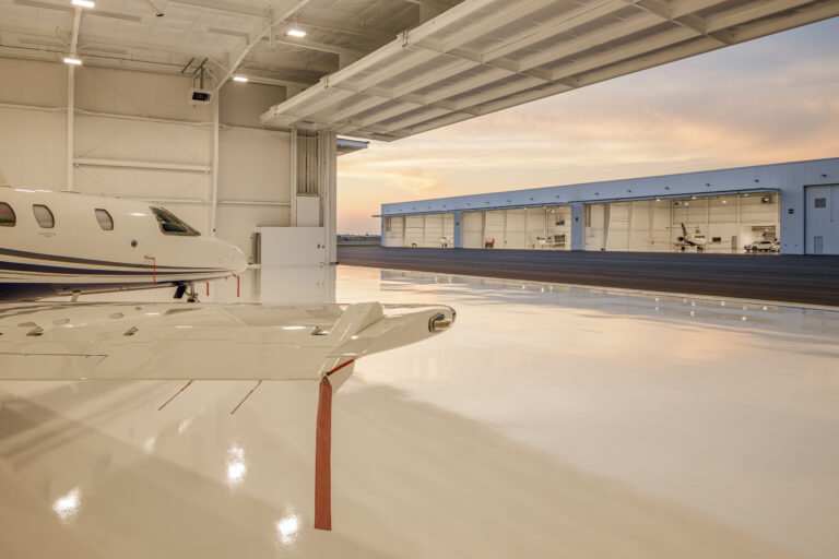 Hangar interior looking out toward more hangars, with a private jet wing in the foreground